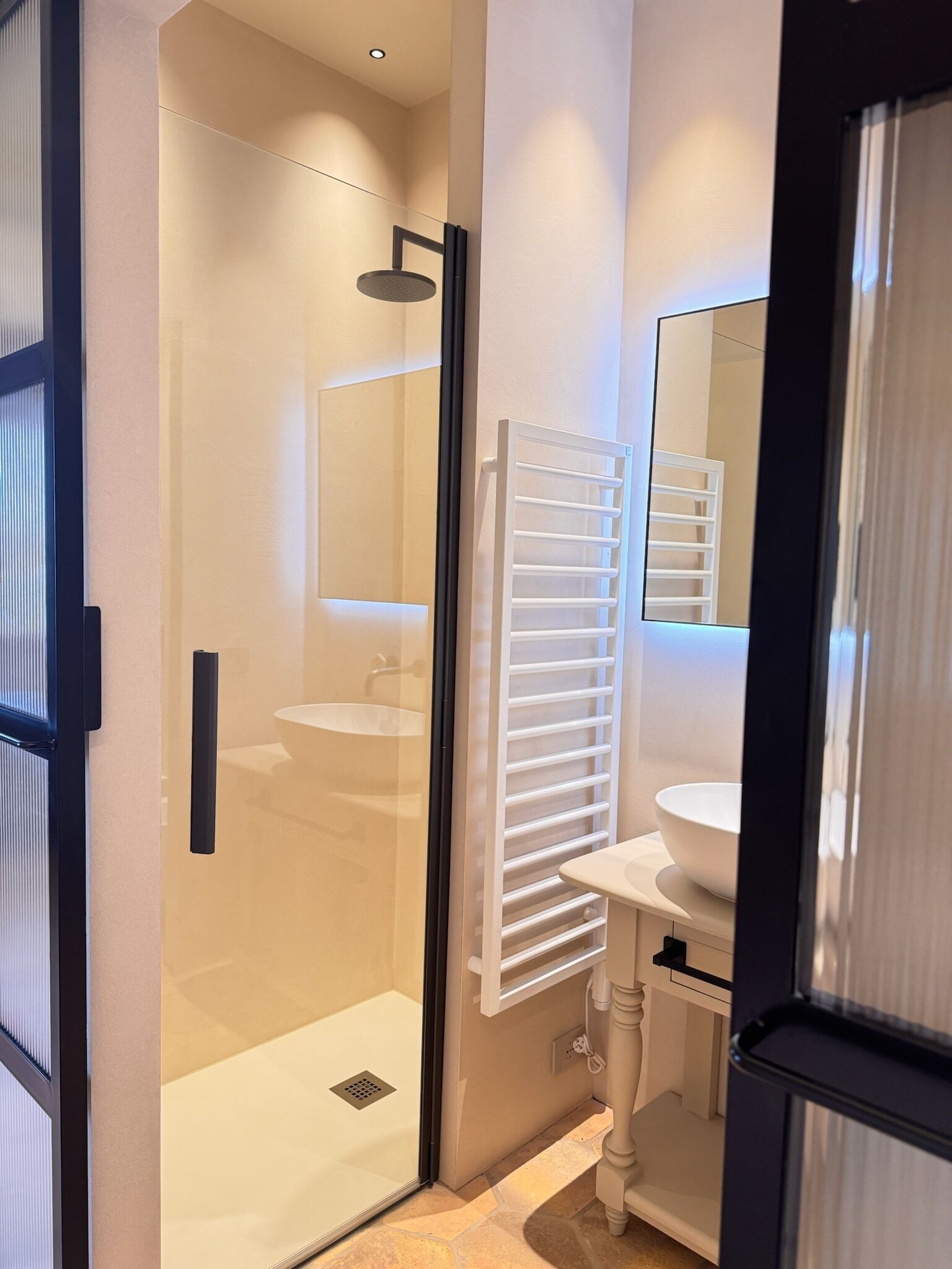 Une salle de bain moderne avec une douche à parois de verre, un lavabo blanc et un porte-serviettes.