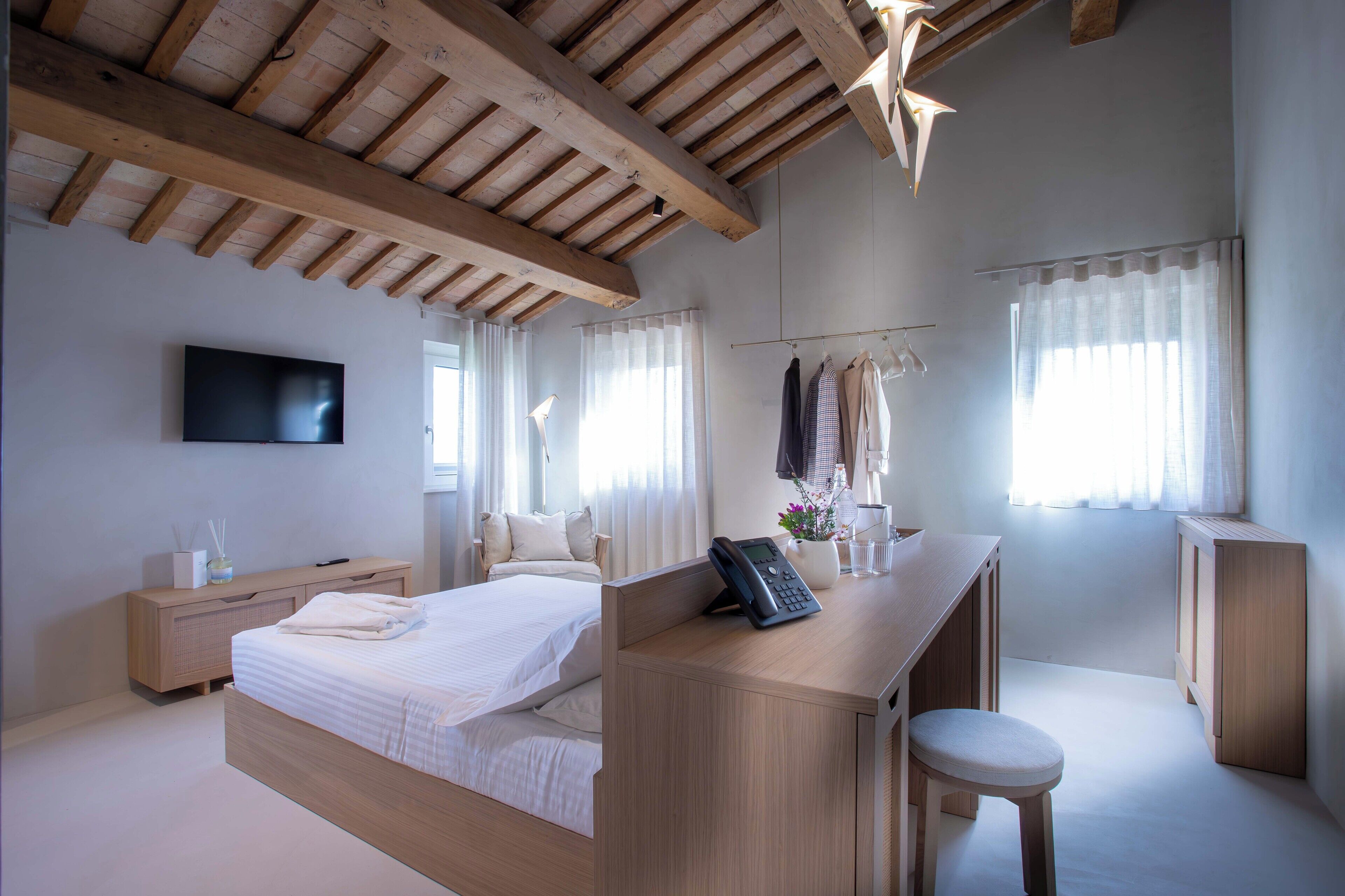 Ein modernes Schlafzimmer mit einem großen Bett, einem Schreibtisch, einem Stuhl und einem Fernseher.