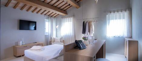 A modern bedroom with a large bed, a desk, a chair, and a TV.