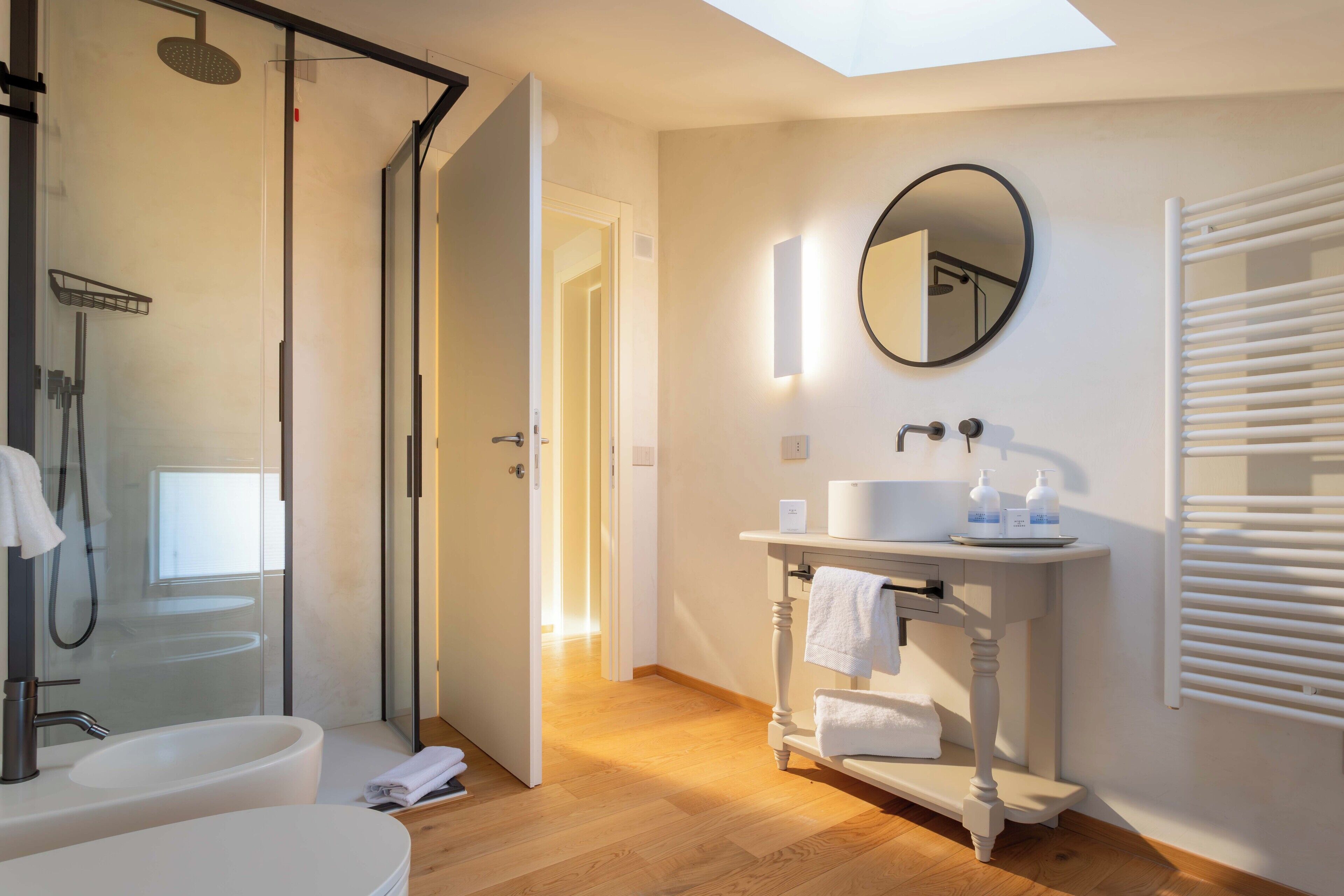 Un baño moderno con ducha envuelta en vidrio, un lavabo blanco y un tocador con espejo.