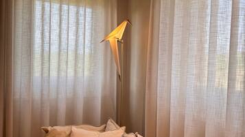 A cozy room with a bed, a floor lamp, and sheer curtains.