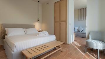 Ein Schlafzimmer mit Bett, Nachttisch, Bank, Kleiderschrank und Stuhl.