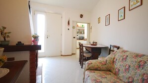 Una sala de estar con un sofá floral, una mesa de centro de madera y un comedor con sillas y una mesa.