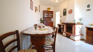 Un comedor con una mesa redonda de madera, sillas estampadas con motivos florales y un mantel de encaje.