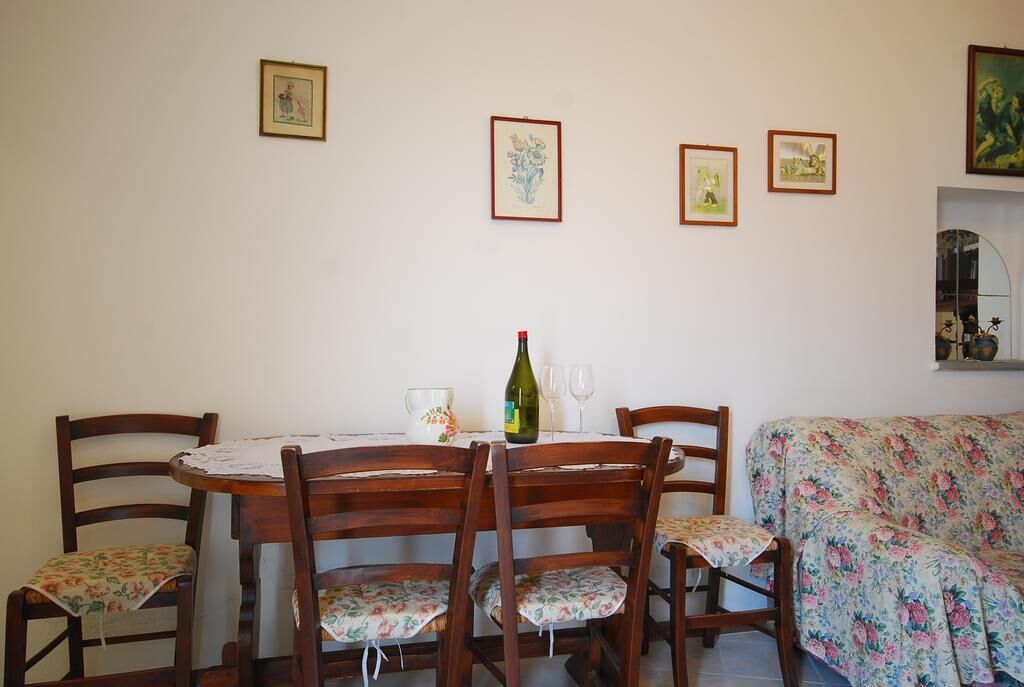 Un coin repas avec une table ronde en bois, quatre chaises et un canapé à motifs floraux.