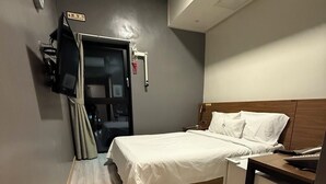 A hotel room with a bed, bedside table, and a television mounted on the wall. - Samcheok NS Hostel & Motel  (Samcheok)