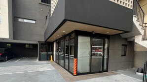A modern building with a glass entrance, a parking lot, and a staircase. - Samcheok NS Hostel & Motel  (Samcheok)