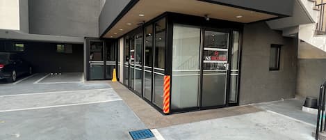 A modern building with a glass entrance, a parking lot, and a staircase.