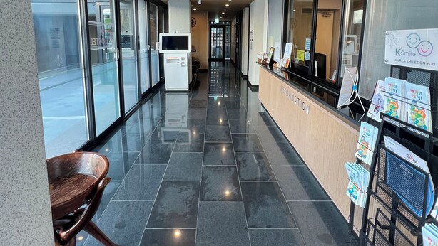 A clean, modern lobby with a reception desk, a wooden chair, and a bulletin board with pamphlets. - Samcheok NS Hostel & Motel  (Samcheok)