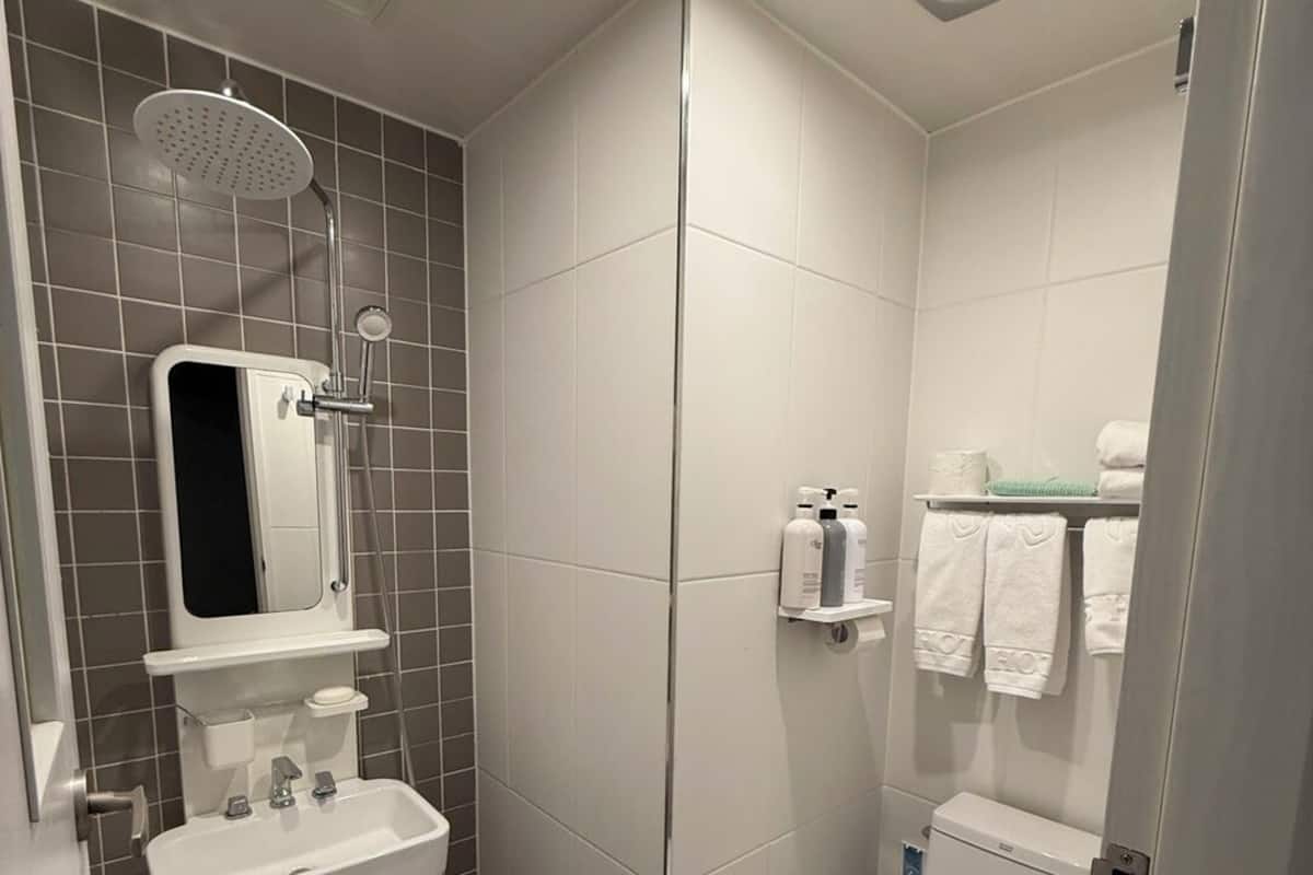 Un baño moderno con ducha, lavamanos, inodoro y perchero para toallas.