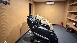 A massage room with two massage chairs, a fire extinguisher, and a shelf with items. - Samcheok NS Hostel & Motel  (Samcheok)