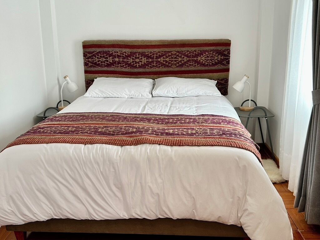 A bed with a patterned headboard, white bedding, and two bedside lamps.
