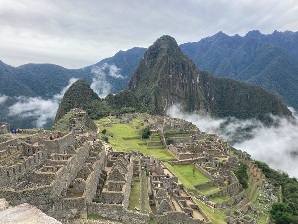 An ancient stone city with terraced structures and a mountainous backdrop.