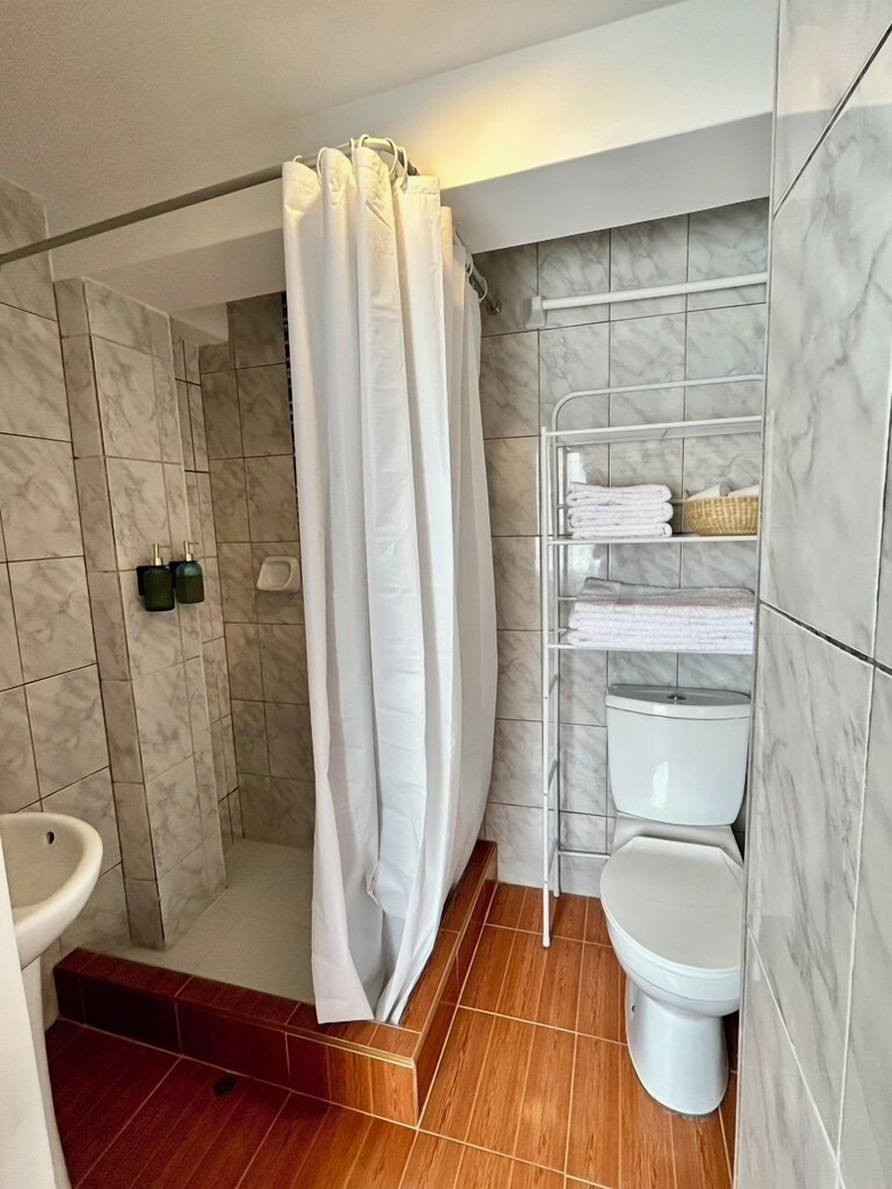 Une salle de bain moderne équipée d’une douche, de toilettes et d’étagères de rangement.