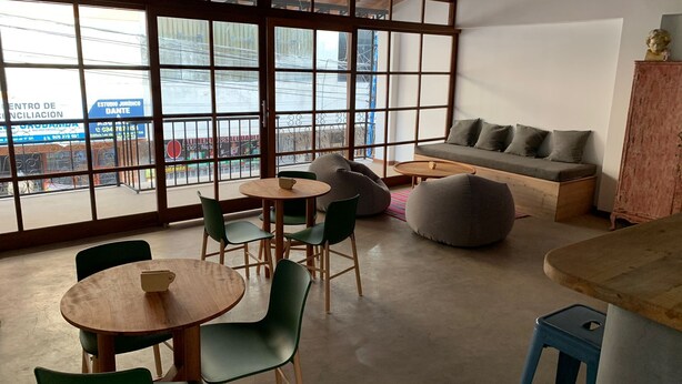 A modern interior with large windows, a sofa, green chairs, and a wooden table. - La Maison Samaï (Urubamba)