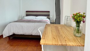 A bedroom with a bed, a wooden table, a vase with flowers, and a nightstand. - La Maison Samaï (Urubamba)