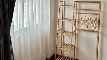 Une pièce avec un étendoir en bois, un tapis à motifs et une fenêtre ornée de rideaux légers.