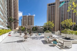 A rooftop patio area with outdoor seating, a fire feature, and a view of tall buildings.