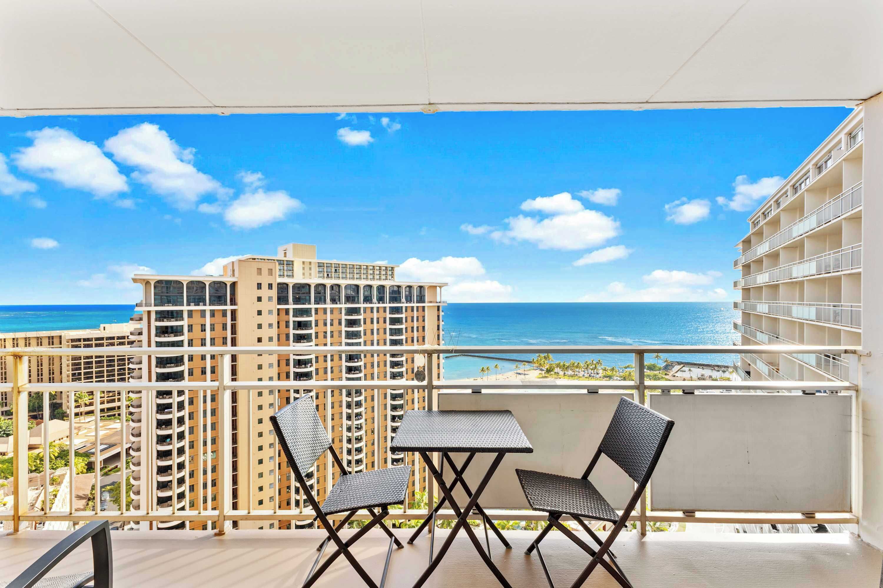 A balcony with a view of the ocean and high-rise buildings.