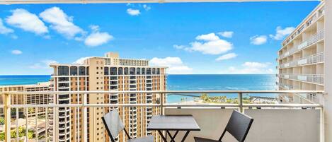 A balcony with a view of the ocean and high-rise buildings.