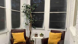 A corner room with two leather armchairs, a small table with a plant, and a window with a view of trees. - A Stay That Feels Like Home - 10 Minutes to the Capitol & National Mall (Washington)