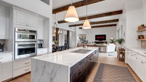 A modern kitchen with white cabinetry, a large island, and a built-in oven. - NEW RENOVATION! A Modern Twist on Southwest Living (Scottsdale)