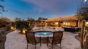 A hot tub surrounded by outdoor seating, a pool, and a patio area with a building in the background. - NEW RENOVATION! A Modern Twist on Southwest Living (Scottsdale)
