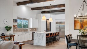 A modern kitchen with white cabinets, a marble island, and pendant lighting. - NEW RENOVATION! A Modern Twist on Southwest Living (Scottsdale)