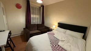 Une chambre à coucher avec un lit, un canapé, un bureau et une fenêtre avec des rideaux.