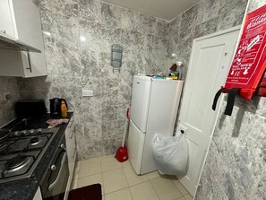 Une cuisine compacte équipée d’une cuisinière à gaz, d’un grille-pain, d’une bouilloire et d’un réfrigérateur.