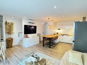 A modern kitchen with a dining area, a flat-screen TV, and a refrigerator. - Villa Paradis 2 Sun Sea and Beach (Valras-Plage)