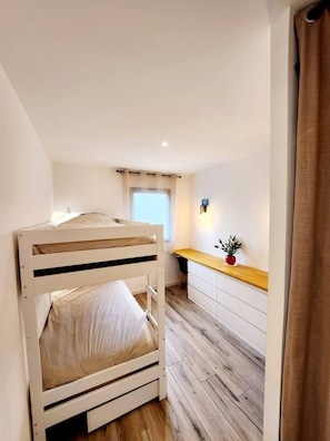 A bunk bed with a desk and chair, a window with curtains, and a small plant on the desk. - Villa Paradis 2 Sun Sea and Beach (Valras-Plage)