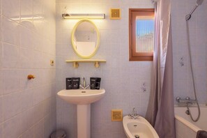 Une salle de bain équipée d’un lavabo, d’un miroir, d’une douche et de toilettes.