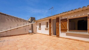 Un edificio residencial con un patio empedrado, puertas de madera y una ventana.