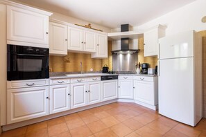 A kitchen with white cabinets, a stainless steel range hood, a dishwasher, and a refrigerator. - Village House near the Canal (Colombiers)
