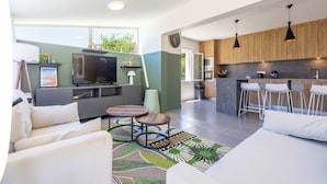 A modern living space with a TV, seating area, kitchen, and bar stools. - Villa Familiale avec Piscine et Petanque (Valras-Plage)