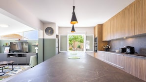 A modern kitchen with a marble countertop, wooden cabinets, and a pendant light. - Villa Familiale avec Piscine et Petanque (Valras-Plage)