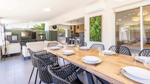 A modern dining area with a long wooden table set for six, surrounded by black chairs. - Villa Familiale avec Piscine et Petanque (Valras-Plage)