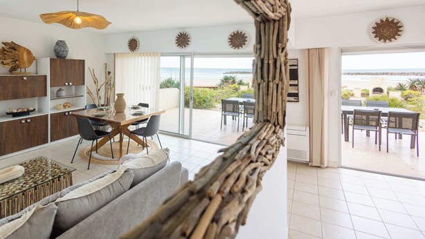 Un salon moderne avec un coin repas, de grandes fenêtres et une vue sur la mer.
