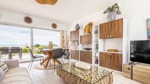 Un salon moderne avec une table basse en verre, des meubles en bois et un téléviseur.