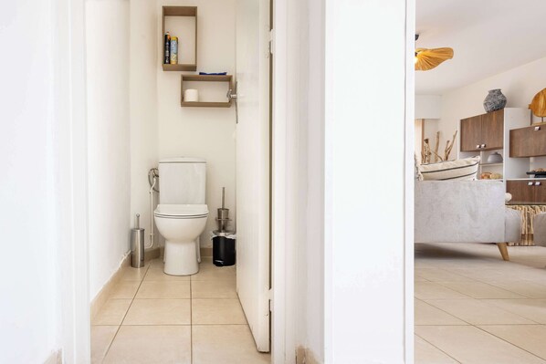 A modern bathroom with a toilet, bidet, and storage shelves.