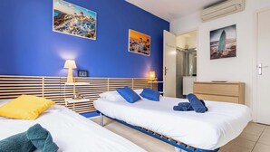 Une chambre d’hôtel avec deux lits, une tête de lit en bois, une table de chevet, une lampe et un miroir.
