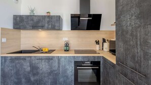 A modern kitchen with a built-in oven, a sink, and a countertop with a kettle.