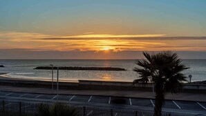 A sunset over the ocean with a palm tree in the foreground. - Valras'Loc Archipel Capri Balcony over the Sea (Valras-Plage)