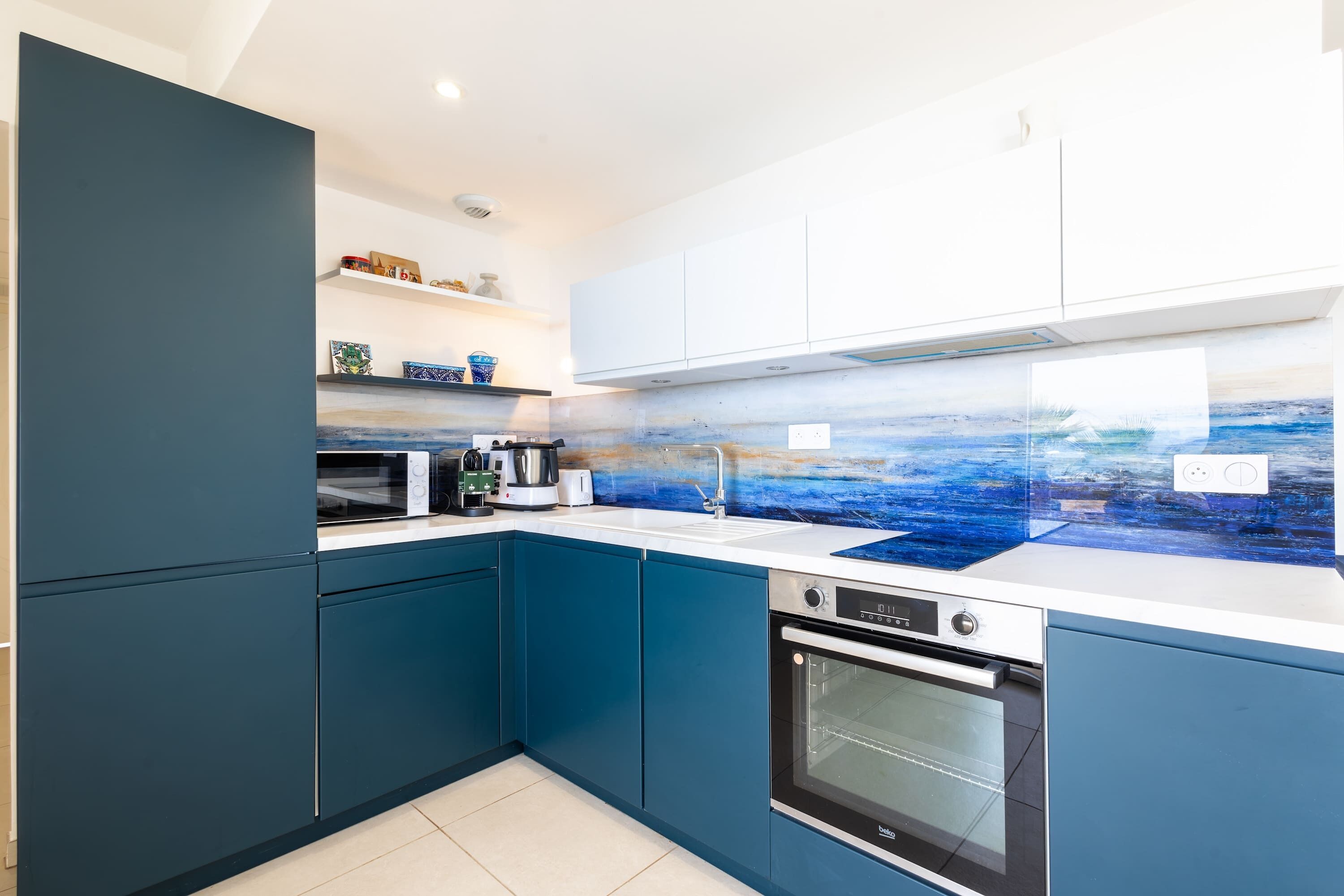Una cocina moderna con armarios azules, un microondas, un hervidor y una estufa.