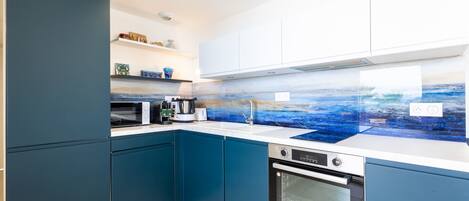 Una cocina moderna con armarios azules, un microondas, un hervidor y una estufa.