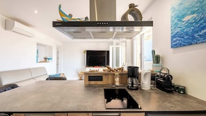 A modern kitchen with a central island, built-in oven, and a large window.