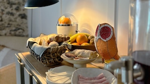 A kitchen counter with a variety of food items, including bread, pastries, fruits, and a decorative bird figure. - Live Sintra Boutique Guest House (Sintra)