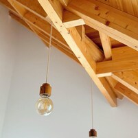 Estructura de techo de madera con vigas a la vista y lámparas colgantes.