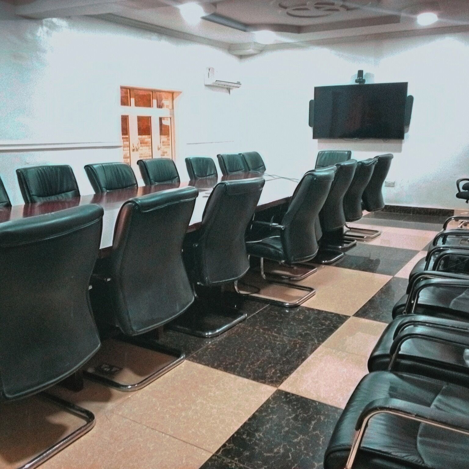 A conference room with a long table and multiple chairs arranged around it.